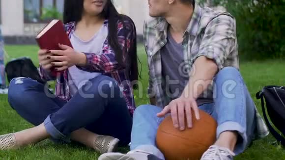 带着书的女孩带着篮球坐在草地上聊天的男人关系视频的预览图