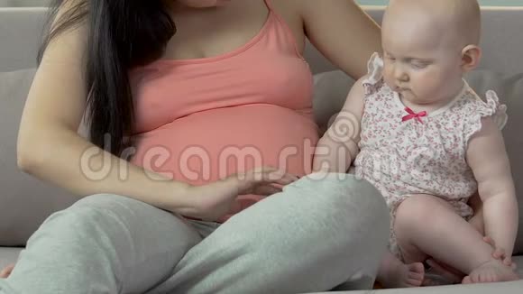 孕妇和婴儿坐在沙发上女性在儿童手臂上行走手指视频的预览图