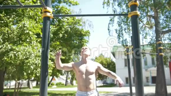 夏季公园里运动的年轻肌肉男在横杠上拉起来视频的预览图