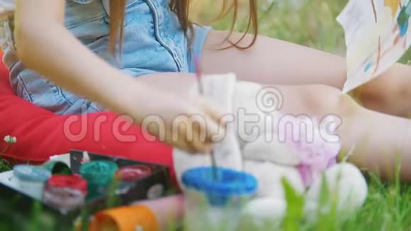 夏天坐在草地上用画笔画孩子的手视频的预览图
