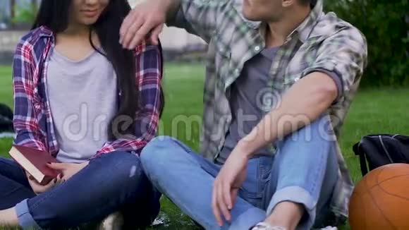 学生们坐在草地上男人牵着女孩的手约着浪漫的约会视频的预览图