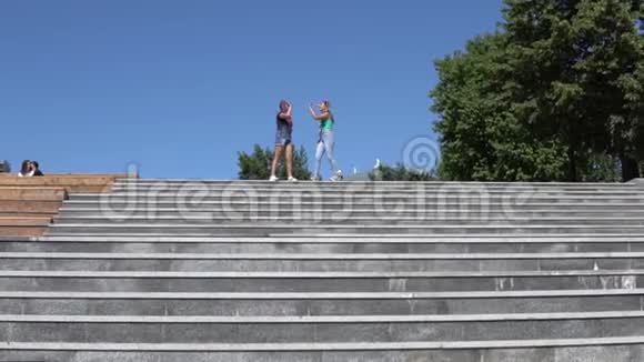 两个漂亮的女朋友高兴地站在街上的台阶上跳着视频的预览图
