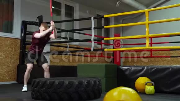 强壮的肌肉男在健身房里用大锤敲打轮胎视频的预览图