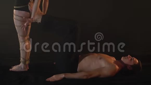 一个被绳子绑着的女人躺在工作室里一个男人的脚上视频的预览图