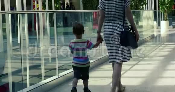 妇女和蹒跚学步的儿子走路的后视图视频的预览图