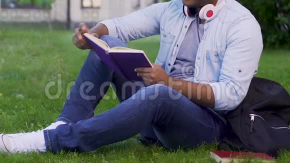多种族男子坐在草地上读书娱乐活动书虫视频的预览图