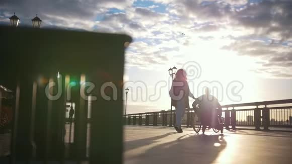有残疾男子坐轮椅的年轻女子走到长凳旁边视频的预览图