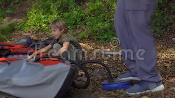 一个年轻人和他的小儿子在湖边或海边准备了一个大充气皮艇游泳视频的预览图