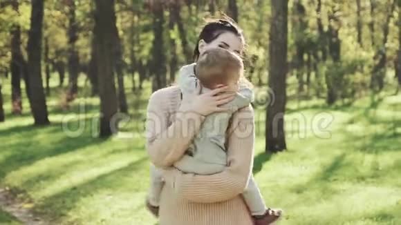 在秋天的公园里年轻的母亲和她的儿子在怀里旋转视频的预览图