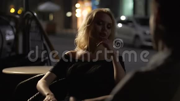 漂亮的金发女郎和男人坐在酒吧露台上无聊的约会晚上视频的预览图