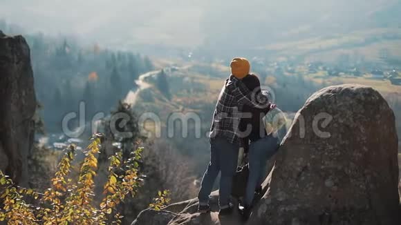 年轻的旅游夫妇相爱站在岩石上欣赏美丽的景色拜访著名游客的男人和女人视频的预览图