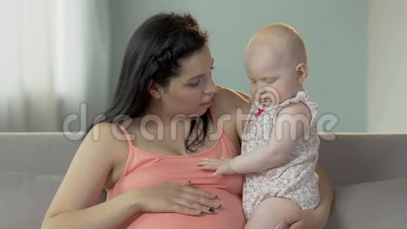 期待女人抱着婴儿揉着肚子和孩子说话做母亲视频的预览图