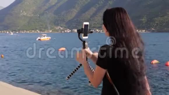 一位年轻女子用稳定器拍摄手机上的风景视频的预览图
