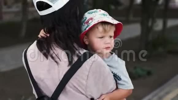 一位慈爱的母亲抱着她疲惫而无聊的孩子同情地拍拍他视频的预览图