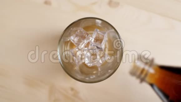 从米色背景的瓶子中倒入冰冷的苏打水慢动作视频的预览图