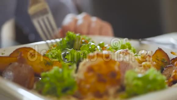 一个男人的手在刀叉的帮助下在餐馆里吃沙拉和牛排视频的预览图