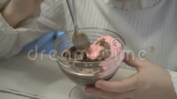一个小女孩坐在咖啡馆里把冰淇淋混合在杯子里吃特写高细节视频的预览图