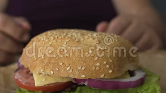 男人从桌子上拿着西红柿和洋葱的汉堡包体重增加宏观视频的预览图
