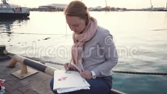 年轻的艺术家在海边的水彩纸上画彩色记号视频的预览图