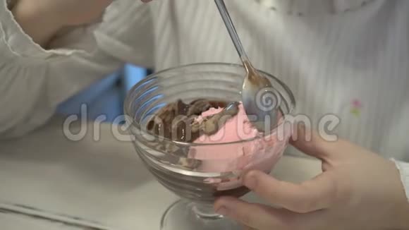 小女孩在杯中混合巧克力和草莓冰淇淋特写高细节视频的预览图