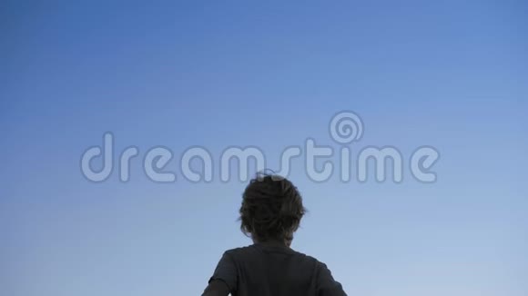 孩子的剪影在蓝天背景上举起双手视频的预览图