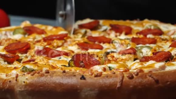 用一个比萨饼切割器将美味的比萨饼与意大利腊肠奶酪和腌制黄瓜切成薄片在白手套中为厨师做特写视频的预览图