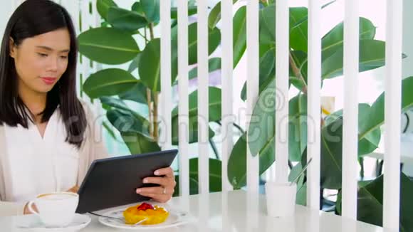 有平板电脑的亚洲女人在咖啡馆或咖啡店视频的预览图