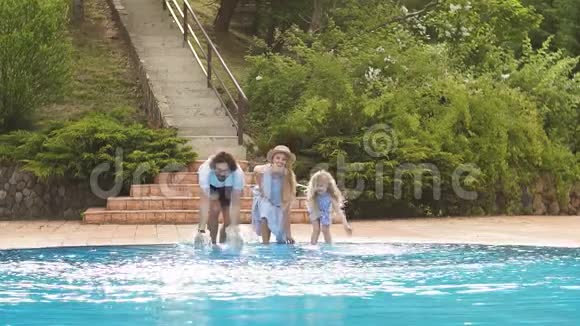一家人玩他们的游泳池家庭用双腿或双手泼水游泳池视频的预览图