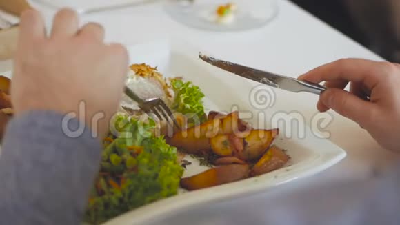 一个男人的手在刀叉的帮助下在餐馆里吃沙拉和牛排视频的预览图