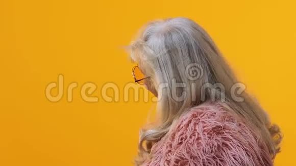 时尚的老年女性戴粉红色眼镜皮毛背景明亮模特视频的预览图