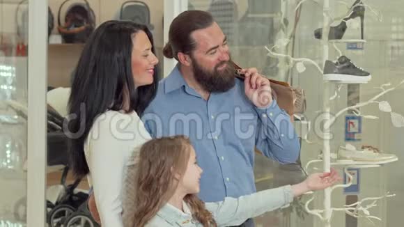 可爱的一家人在购物中心看服装店的陈列视频的预览图