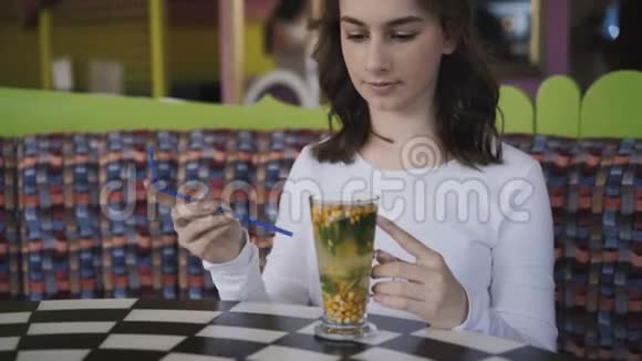 美丽的女孩在咖啡馆里用小管搅拌口味饮料4K视频的预览图