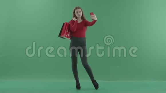 穿着休闲服的漂亮女人拿着购物袋在手机上自拍她站在视频的预览图