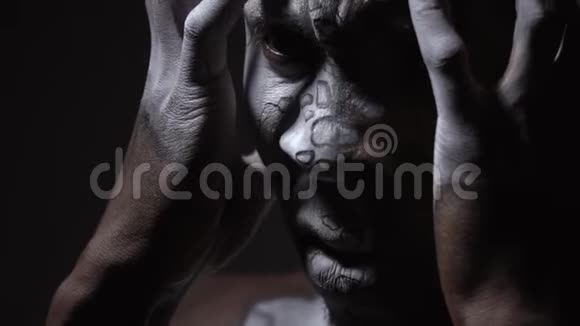 身体上画的非洲人用双手捂住他的脸视频的预览图
