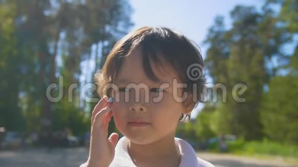 可爱的小男孩在公园的夏日用手指画在脸上画线视频的预览图