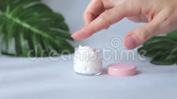 天然面霜装在化妆品罐里女性手试图涂抹奶油视频的预览图
