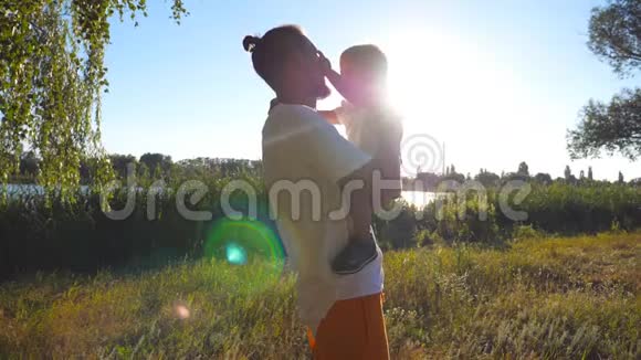 在一个阳光明媚的日子里快乐的爸爸牵着他的金发在公园里的儿子年轻的父亲和他的孩子视频的预览图