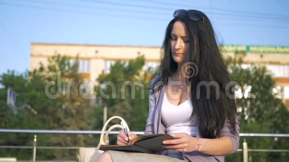 学生在她的笔记本上写了一些东西一个漂亮的黑发女人更喜欢记录信息而不是在现代电子设备中视频的预览图