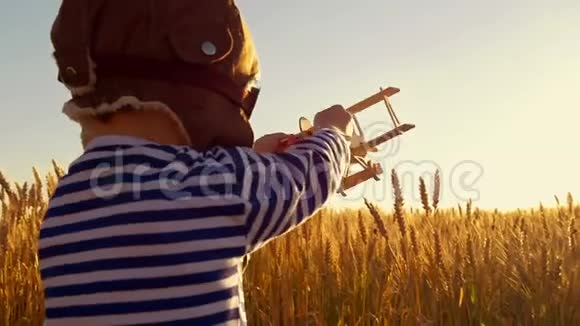 快乐的孩子在日落背景下的麦田里玩玩具飞机这个男孩用一个视频的预览图