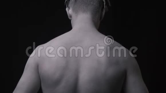 穿着白色颜料摆姿势黑色背景的健康男人的背部视频的预览图