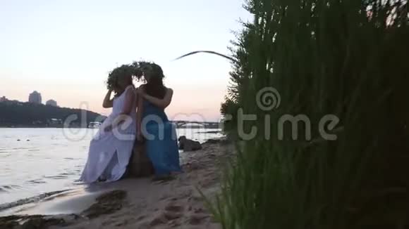 两个美丽的女孩头上戴着花环在河岸上视频的预览图