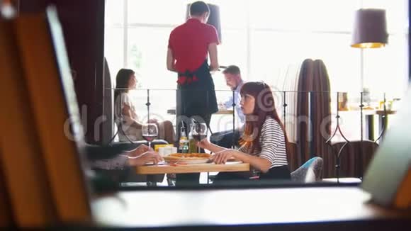 年轻夫妇在餐厅吃午餐交谈服务员接受订单背景视频的预览图