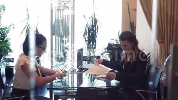 两个女商人在办公室的一张桌子旁讨论一个商业项目视频的预览图