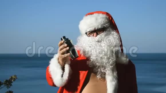 一个穿着圣诞老人服装拿着鸡尾酒的人正在海滨跳舞旅行和度假视频的预览图