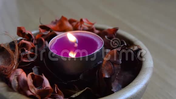 紫色的蜡烛放在一个装满陶器的木碗里视频的预览图