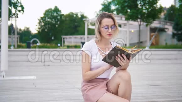 戴眼镜的年轻漂亮女子在公园看书视频的预览图