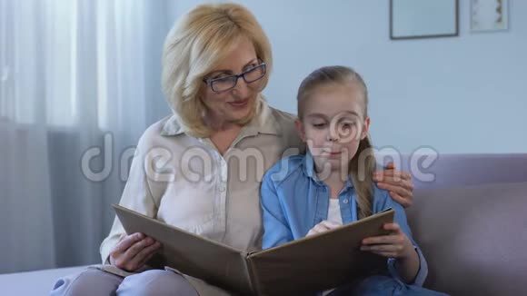 漂亮的小女孩和奶奶在家看书关系很亲密视频的预览图