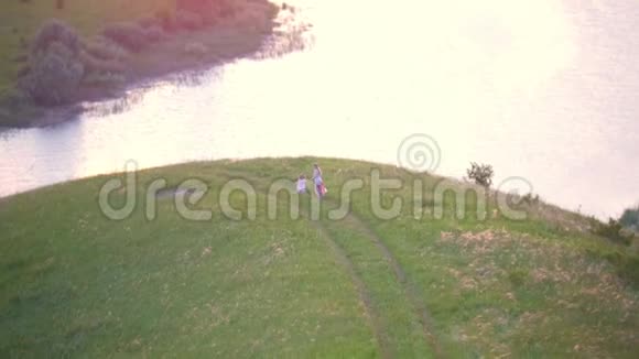 鸟瞰小女孩和她的母亲在河边的山上休息视频的预览图