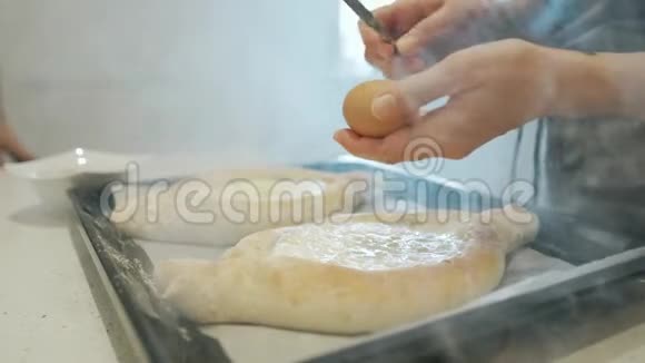 厨师的手打碎了一个鸡蛋贝克双手准备厨房桌子上的卡查普里做格鲁吉亚传统料理的厨师视频的预览图