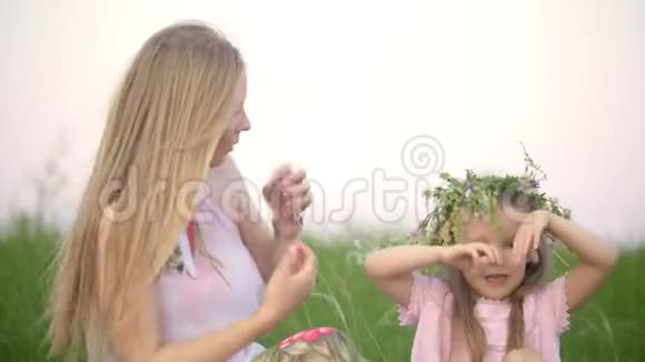 迷人的母亲带着她的小女儿在夏日的草地上用手做一个心形视频的预览图